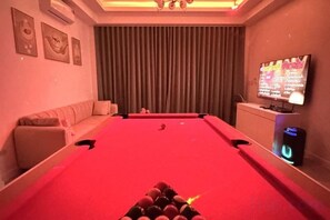 A pool table with a red felt surface, a sofa, a television, and a wall-mounted air conditioner. - The White House Pool Villa Pattaya (Pattaya)