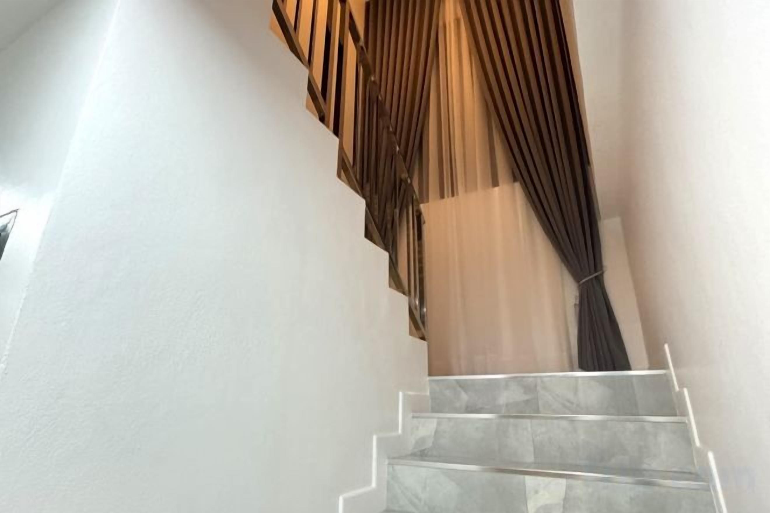 A staircase with a modern design, featuring a white wall and a patterned wall covering.