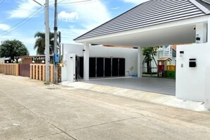 A modern building with a covered parking area, a gated entrance, and a small play area visible through the windows. - The White House Pool Villa Pattaya (Pattaya)