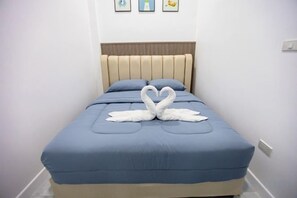 A bed with a blue mattress and a beige headboard, a heart-shaped towel arrangement, and a wall with three framed pictures. - The White House Pool Villa Pattaya (Pattaya)