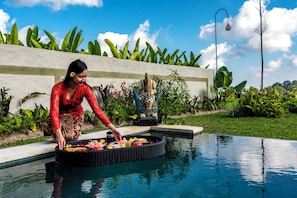 A woman placing a tray of food into a pool.