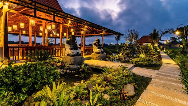 A covered outdoor area with stone statues, a pathway, and lush greenery. - Akshaya Resort Ubud by Dhananjaya Hospitality (Sebatu)