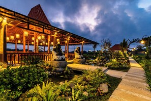 A covered outdoor area with stone statues, a pathway, and lush greenery. - Akshaya Resort Ubud by Dhananjaya Hospitality (Sebatu)