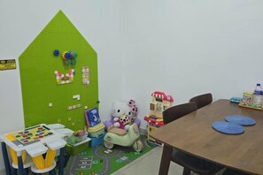 A room with a green wall, a table, chairs, a rocking horse, and a play area with toys. - 2BR@Afiniti(8PAX) 3mins Walk to Legoland (Iskandar Puteri)