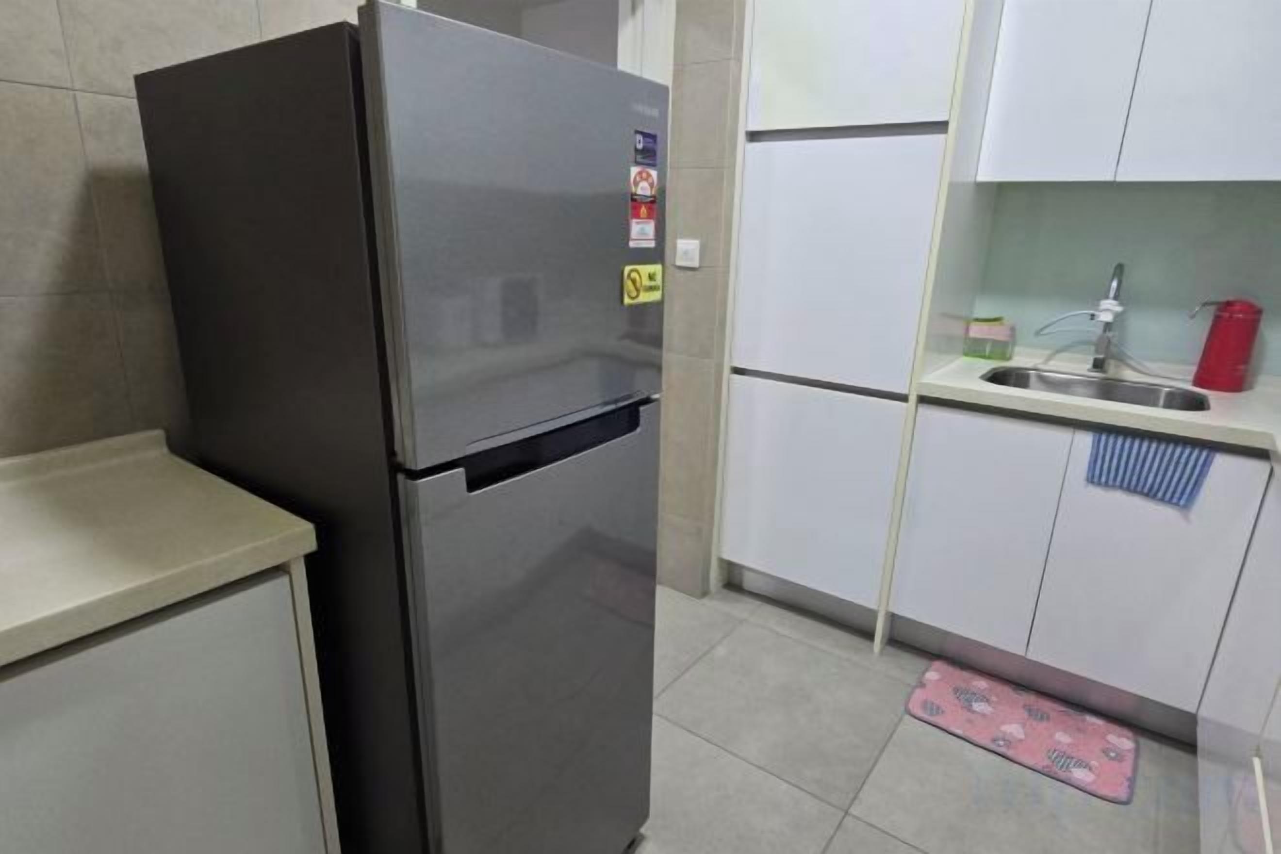 A kitchen with a stainless steel refrigerator, a sink, and a tiled floor.