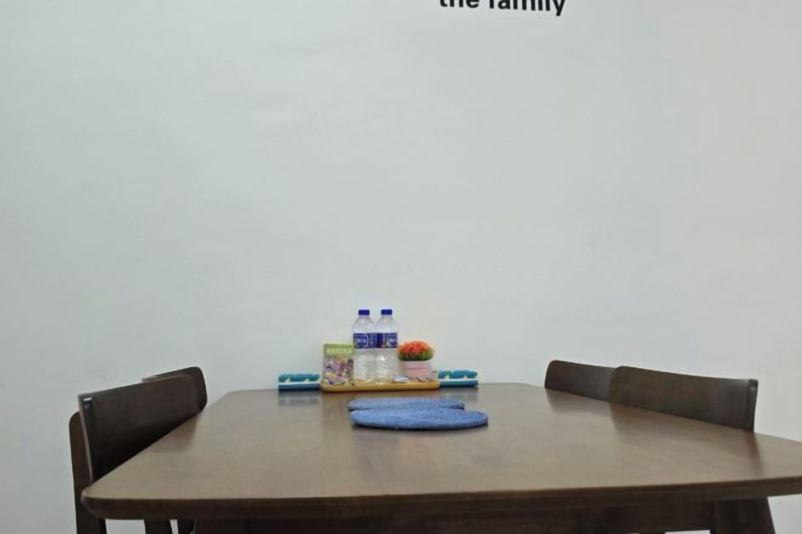 A dining table with four chairs, a tray with water bottles, a box of snacks, and a small potted plant.