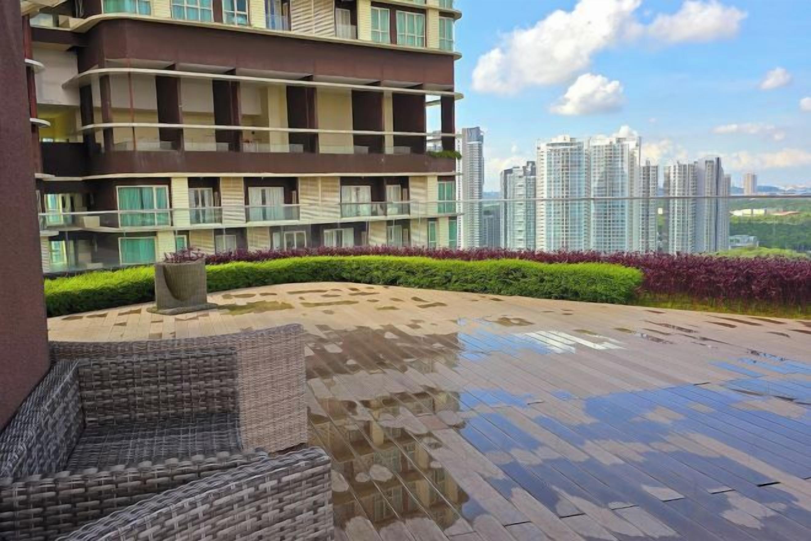 A residential building with a rooftop terrace, a seating area, and a view of high-rise buildings.