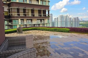 A residential building with a rooftop terrace, a seating area, and a view of high-rise buildings. - 2BR@Afiniti(8PAX) 3mins Walk to Legoland (Iskandar Puteri)