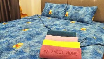 A bed with a blue floral bedspread and two pillows, one with a floral pattern and another with a solid color.