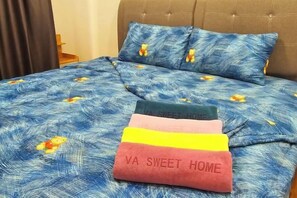 A bed with a blue floral bedspread and two pillows, one with a floral pattern and another with a solid color. - 2BR@Afiniti(8PAX) 3mins Walk to Legoland (Iskandar Puteri)