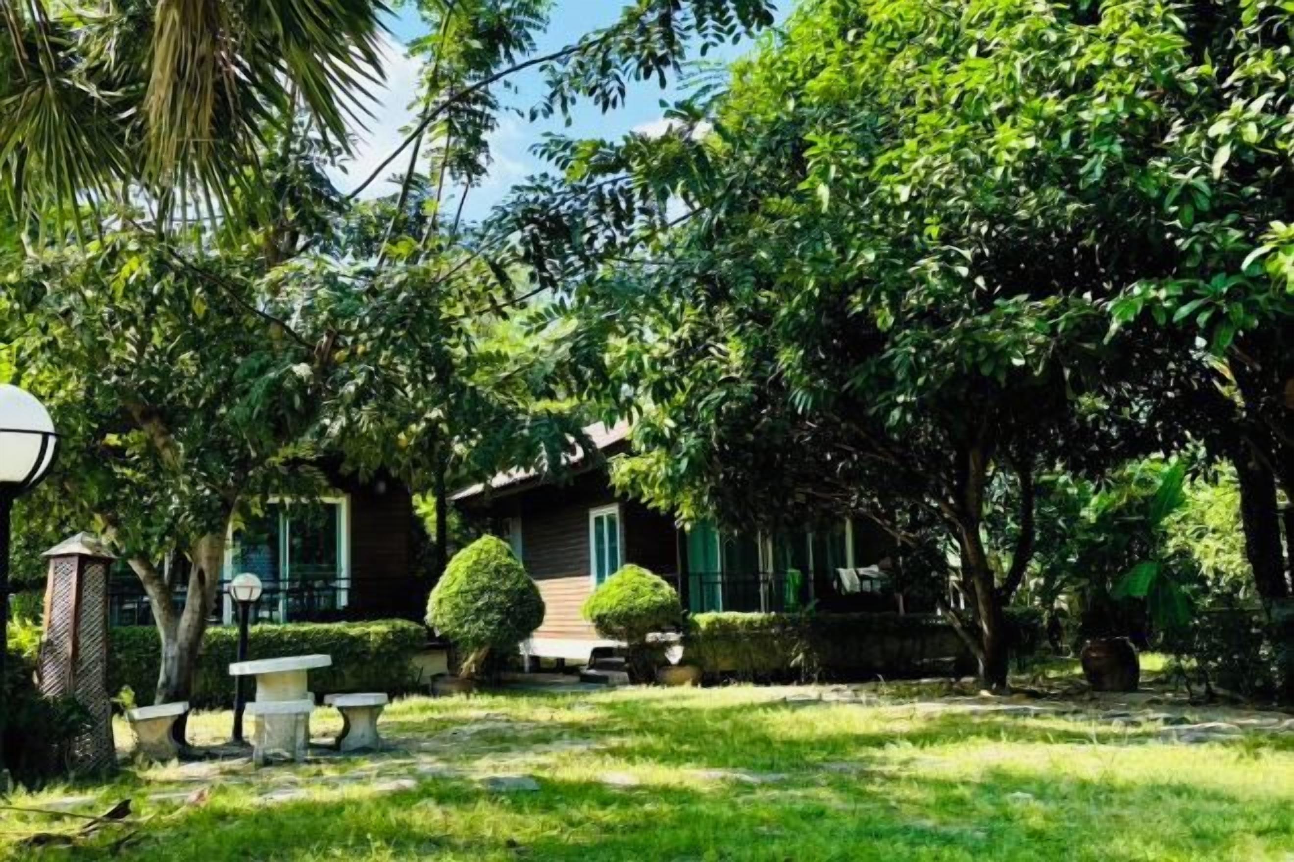 A well-maintained garden with a house, a stone bench, and a lamp post.
