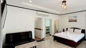 Une chambre d’hôtel moderne, équipée d’un lit, d’une télévision, d’un bureau et d’une salle de bain visible à travers une porte ouverte.