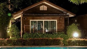 Une maison en bois avec une piscine, entourée de verdure.