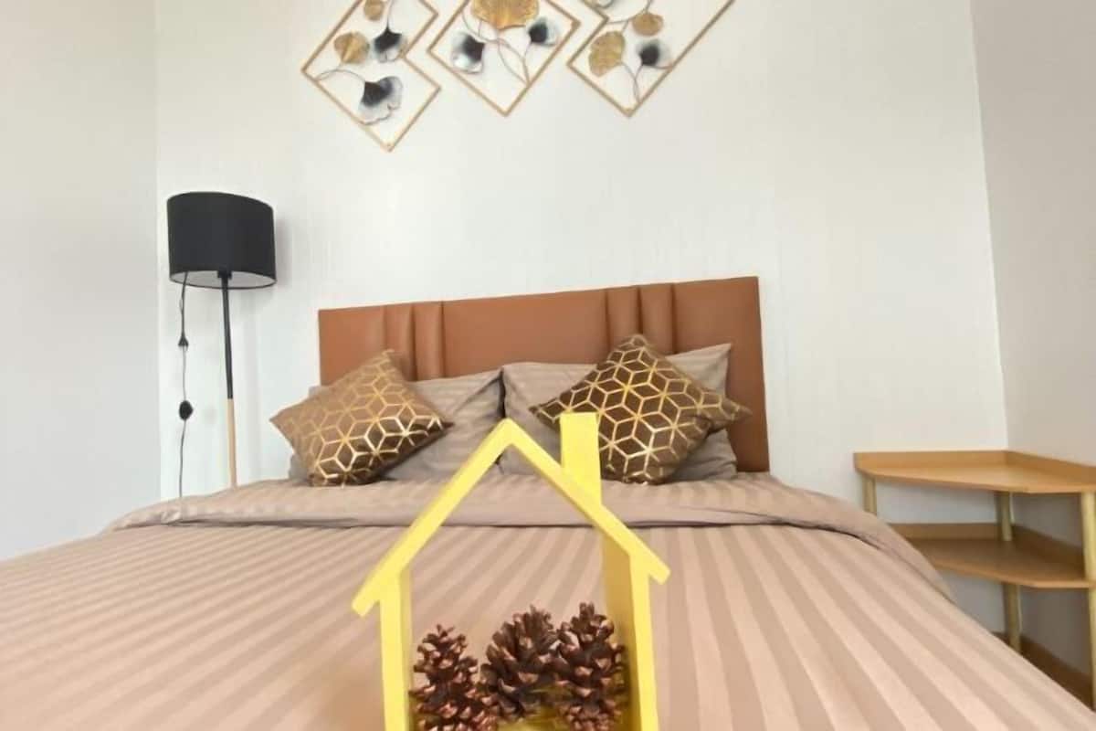 A bed with a striped bedspread, a headboard, and decorative pillows.