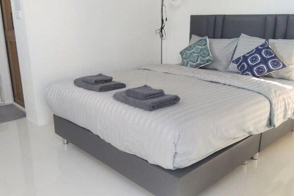 Une chambre à coucher moderne avec un lit gris, une literie blanche et des coussins à motifs.