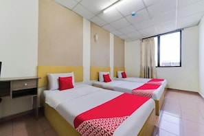 Une chambre d’hôtel avec trois lits, un bureau et une fenêtre.