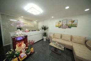 A reception area with a reception desk, a sofa, a coffee table, and a potted plant. - Phu Gia Bui Vien Hotel (Ho Chi Minh City)