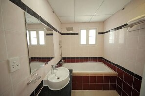 A bathroom with a sink, mirror, bathtub, and window. - Phu Gia Bui Vien Hotel (Ho Chi Minh City)