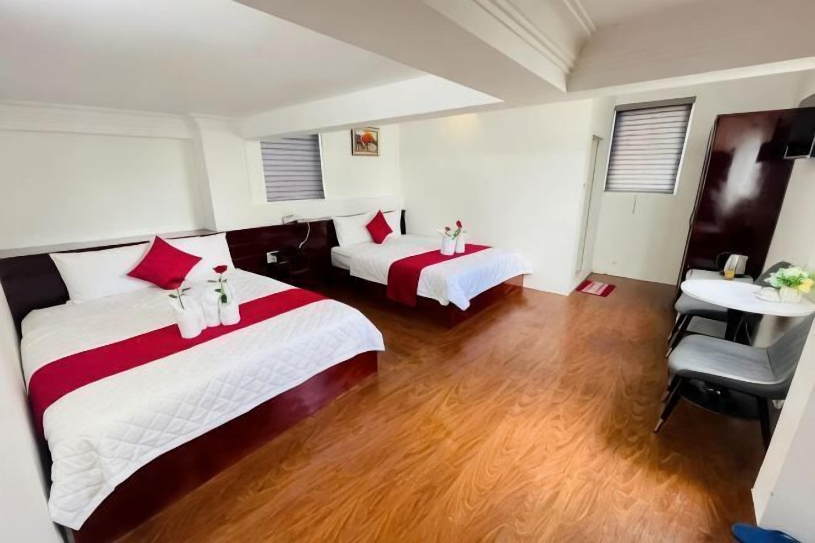 A hotel room with two beds, a desk, and a chair.