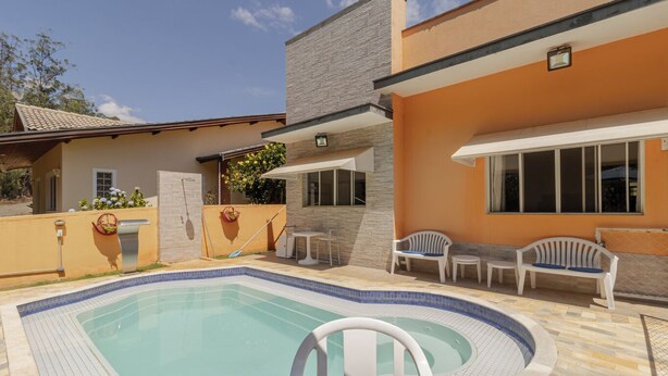 Una piscina con una tumbona, una mesita y dos sillas blancas.