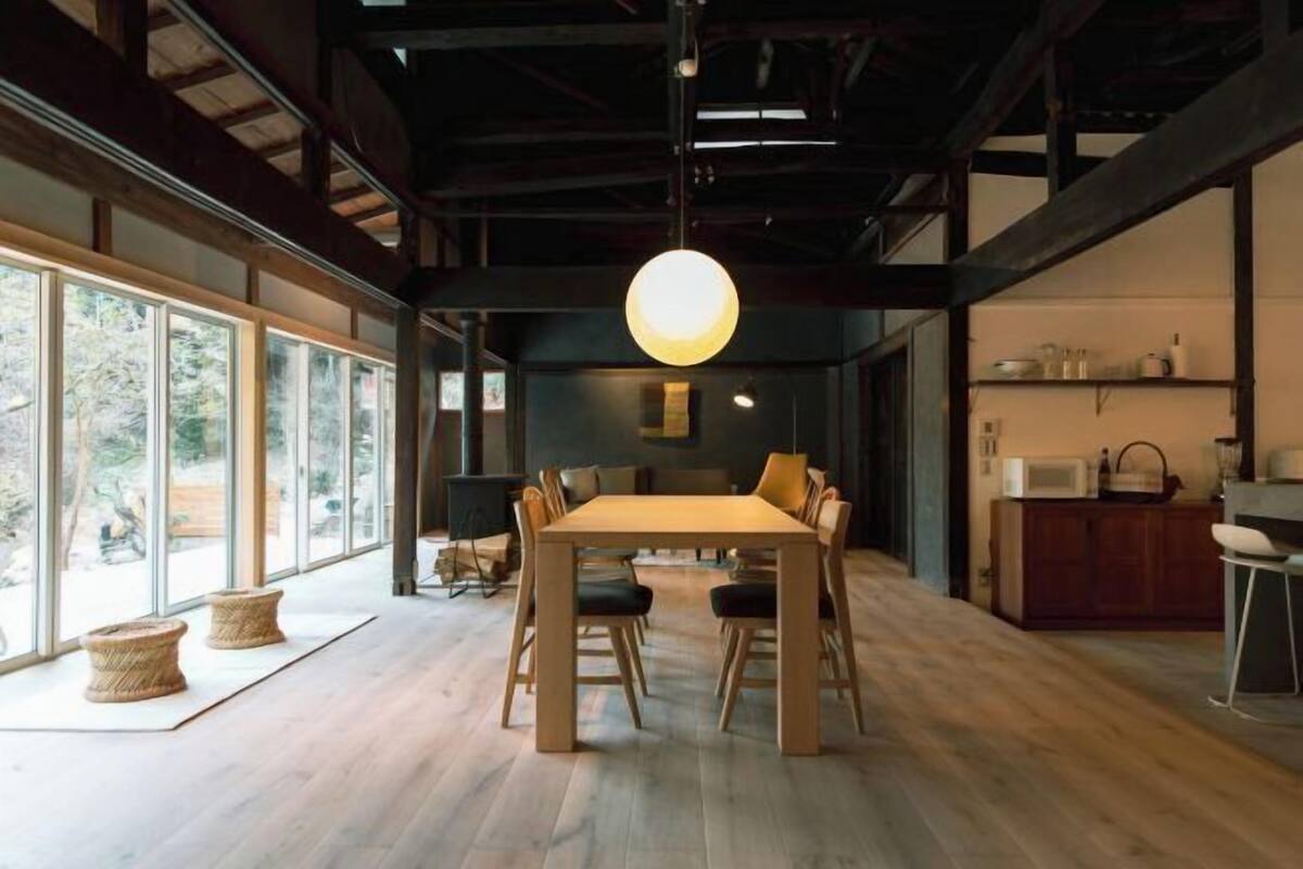 A dining area with a wooden table, chairs, and a hanging light fixture.