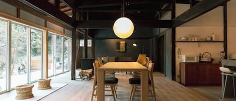 A dining area with a wooden table, chairs, and a hanging light fixture.
