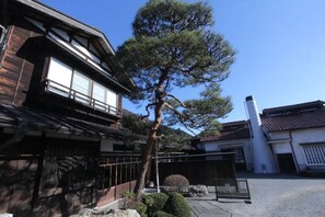 Un edificio japonés tradicional con un gran pino delante.