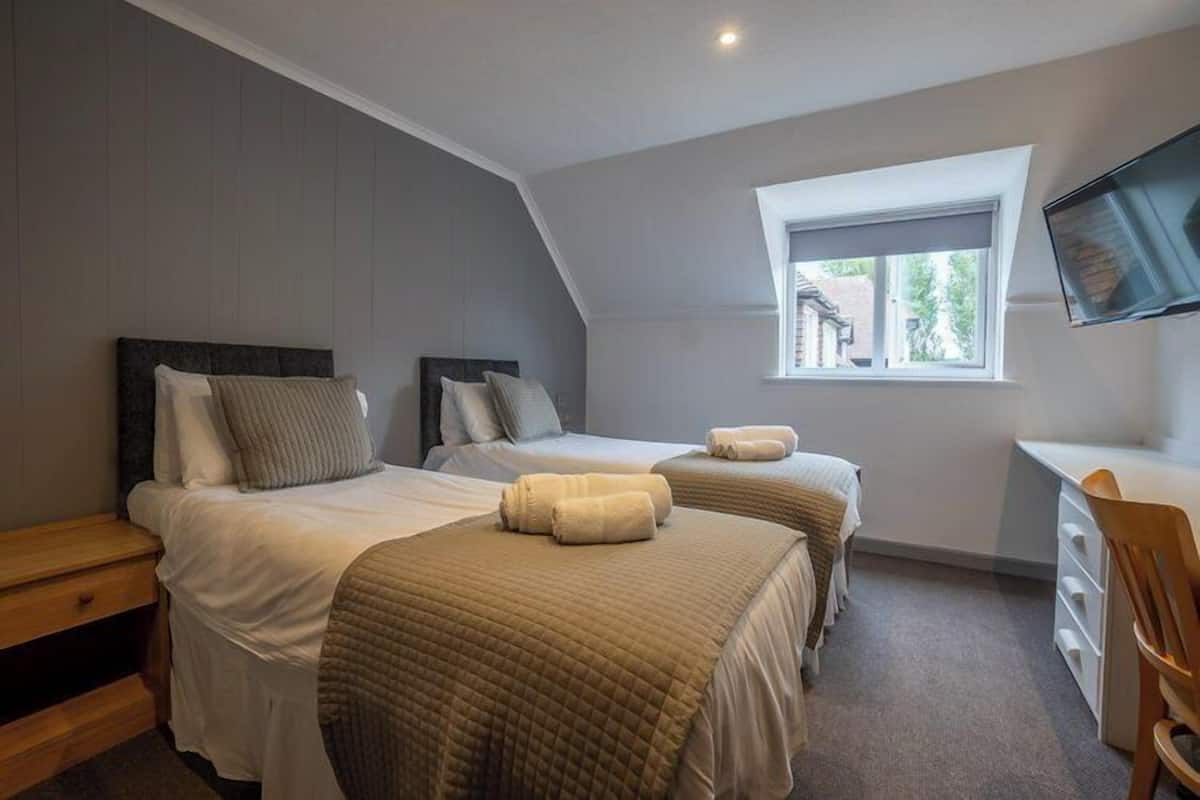 A bedroom with two beds, a desk, and a TV.