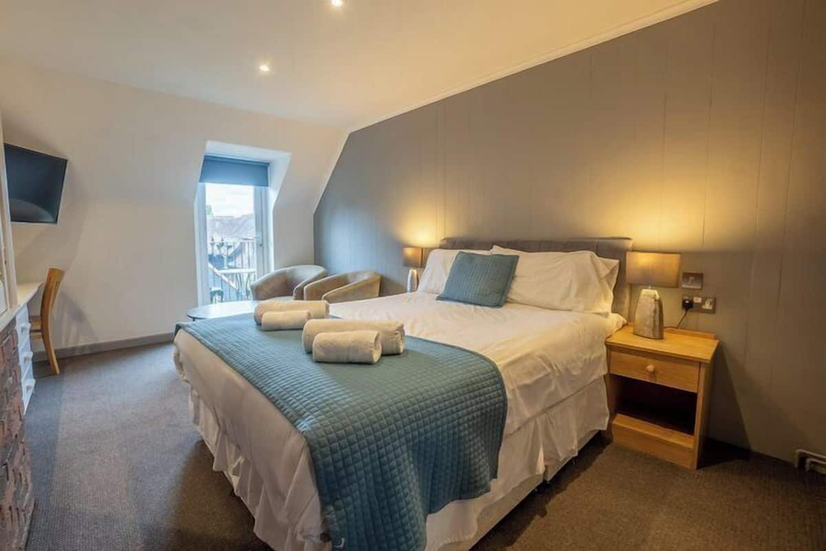 A modern hotel room with a large bed, a desk, and a chair.