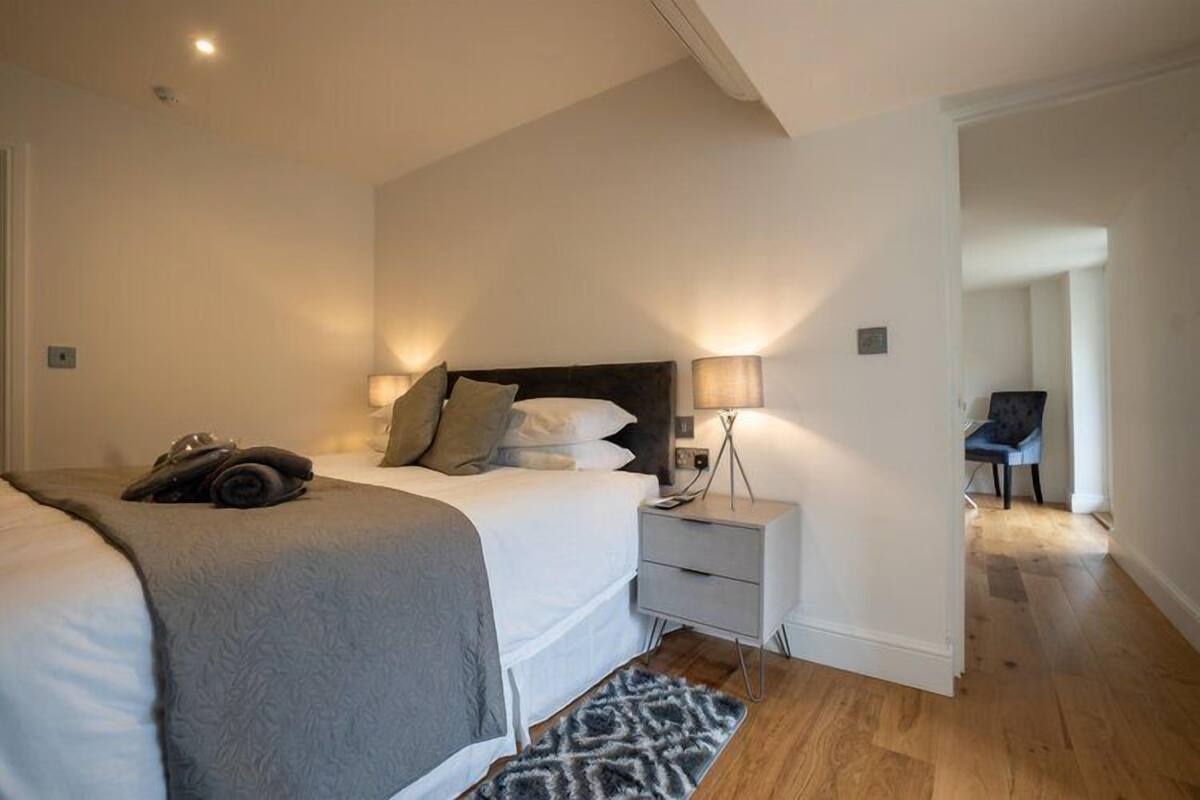 A modern bedroom with a large bed, bedside lamps, and a nightstand.