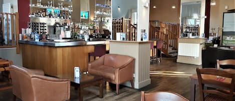 Een bar met een counter, leren stoelen en een houten trap.