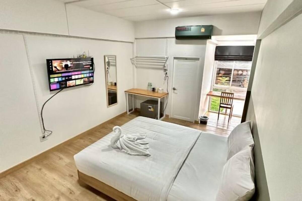 A hotel room with a bed, a desk, a TV, and a window with a view of the outside.