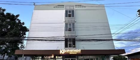 A multi-story building with a sign for 'KP APARTMENT' and a visible entrance.