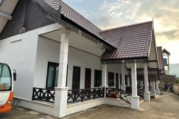 A traditional house with a tiled roof, a porch with a railing, and a staircase leading to the entrance.