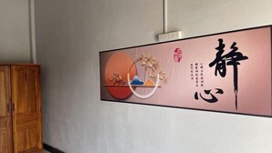 A wall with a large calligraphy piece and a wooden cabinet. - golden sunrise guesthouse (Vang Vieng)