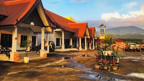 A traditional building with a red-tiled roof, a covered walkway, and a bell tower. - golden sunrise guesthouse (Vang Vieng)