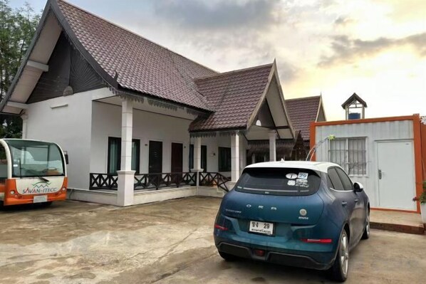 Un edificio con techo de tejas, un porche cubierto y un coche estacionado.