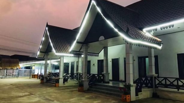 A building with a traditional architectural style, featuring a prominent roof with a unique triangular design and a series of evenly spaced columns supporting a covered walkway. - golden sunrise guesthouse (Vang Vieng)