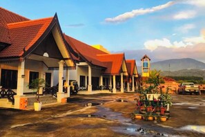 A traditional building with a red roof, multiple rooms, and a small tower structure. - golden sunrise guesthouse (Vang Vieng)