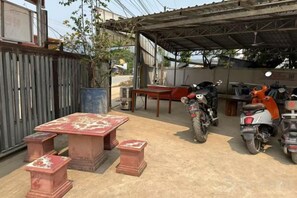Un espacio al aire libre cubierto con una mesa, bancos, una motocicleta y una planta en maceta.