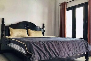 A bed with a dark headboard, two pillows, and a dark bedspread in a room with a window and curtains. - golden sunrise guesthouse (Vang Vieng)