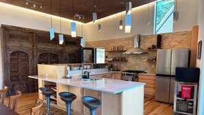 Een moderne keuken met een centraal eiland, barkrukken, een fornuis en een koelkast.