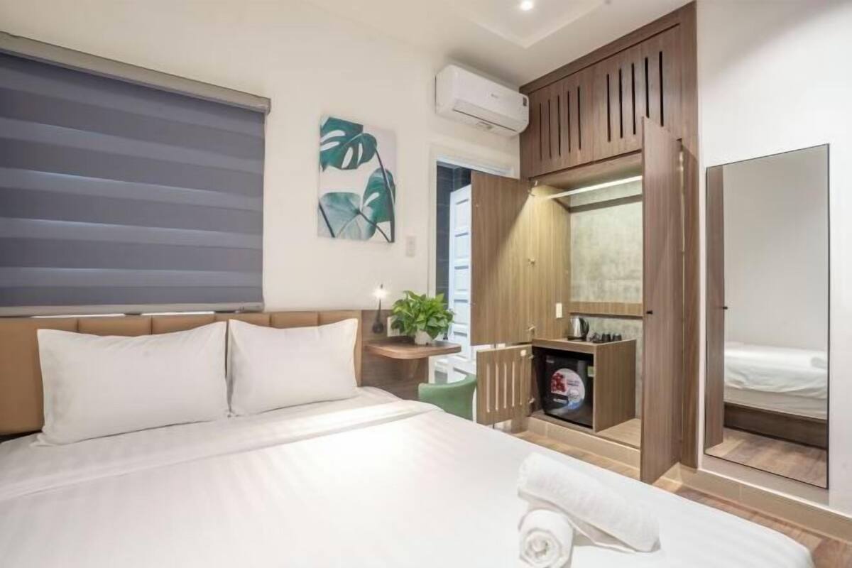 Ein Hotelzimmer mit Bett, Spiegel, Kleiderschrank und einer kleinen Pflanze.