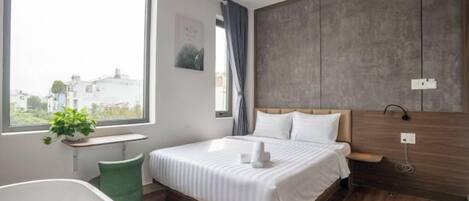 A modern bedroom with a large bed, a window, a green chair, and a wooden wall.