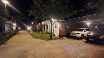 A nighttime parking area with a sidewalk, a building, and two parked cars.