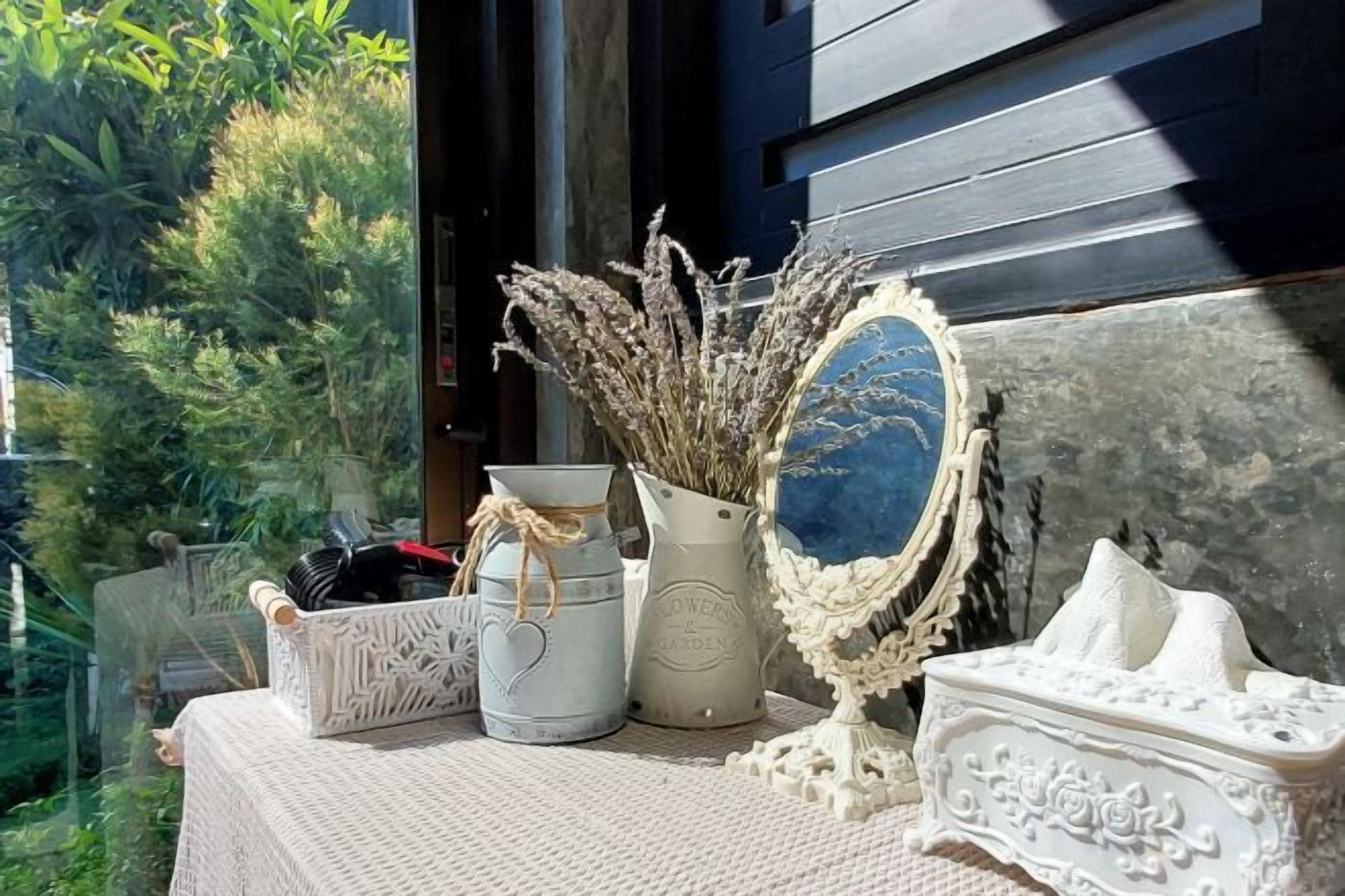 A table with decorative items including a vase with dried plants, a bowl, and a mirror with a blue frame.