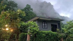 A small, modern house surrounded by lush greenery and dense fog. - Vrapat (Chiang Dao)