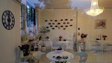 A dining area with round tables, chairs, a chandelier, and wall-mounted decorations.