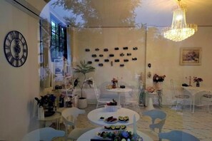 A dining area with round tables, chairs, a chandelier, and wall-mounted decorations. - Vrapat (Chiang Dao)