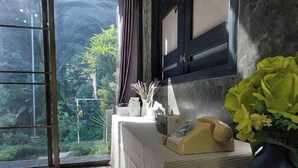 A room with a large window, a telephone, and a vase with flowers. - Vrapat (Chiang Dao)